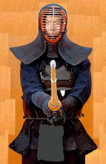 Kendo practitioner in full armor, holding a shinai and facing forward. Demonstrates the angle of the shinai and where the tip points.